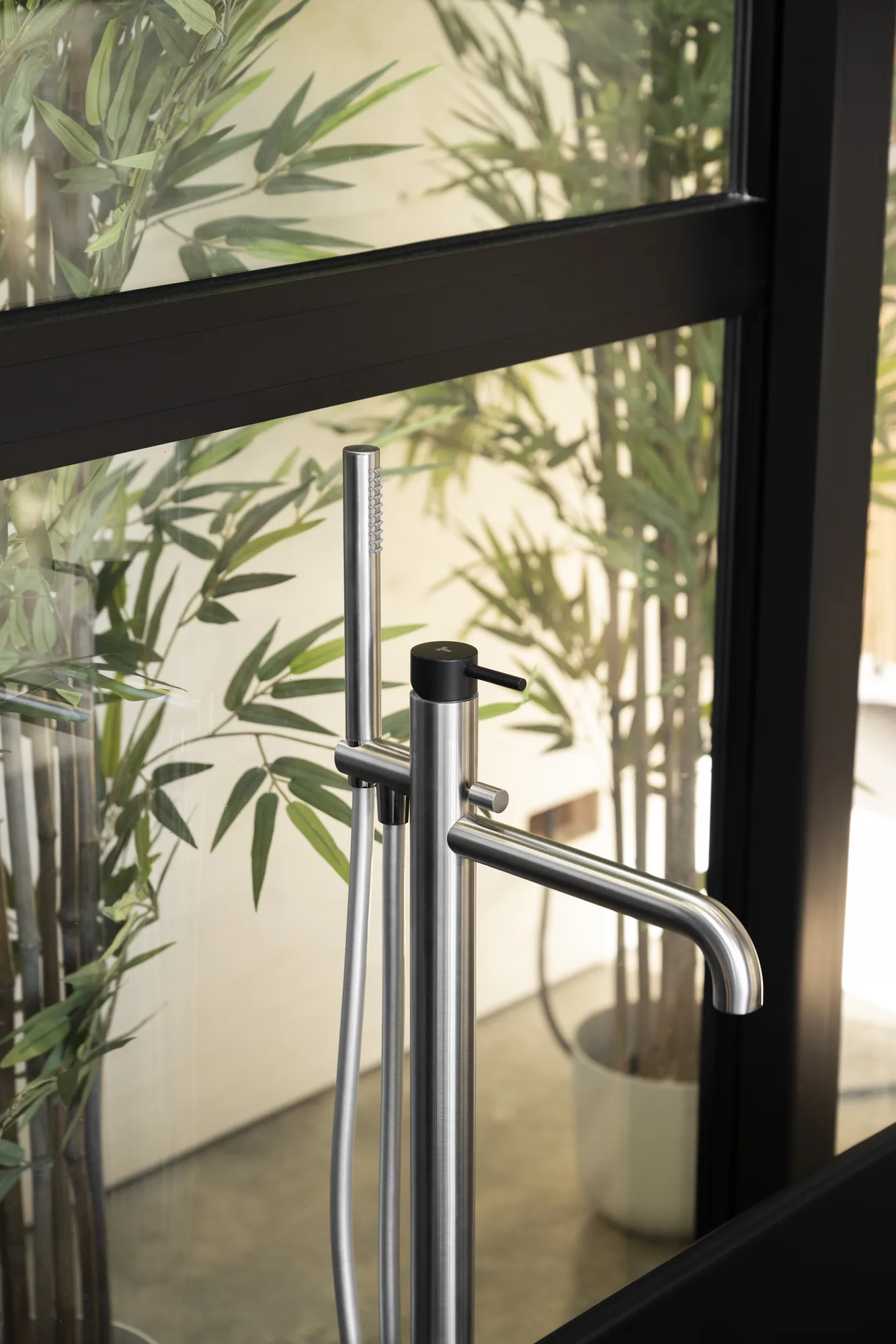 Tubico freestanding floor-mounted bath mixer beside a garden window
