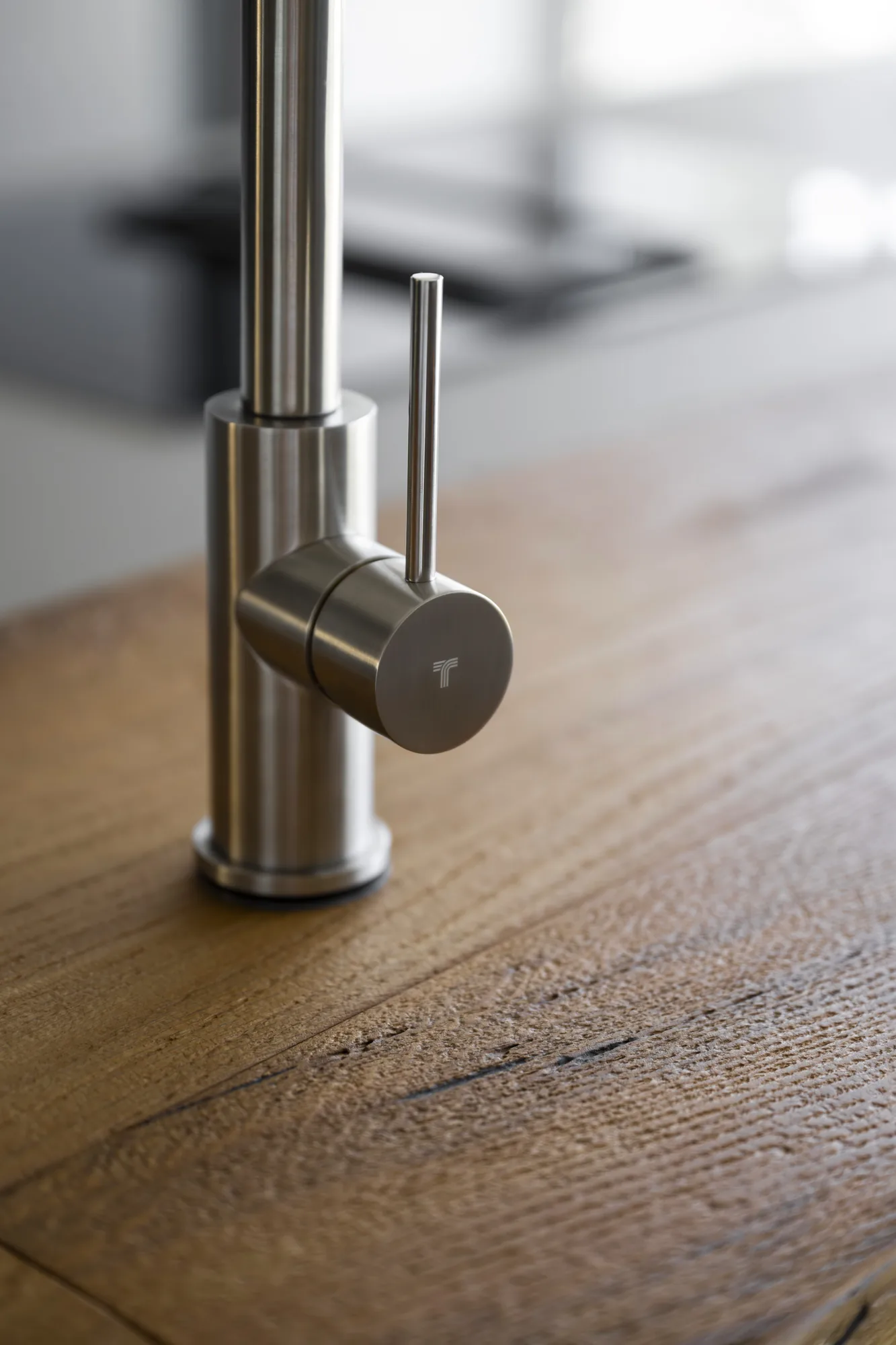 Tubico brushed stainless steel kitchen mixer on a reclaimed-wood worktop