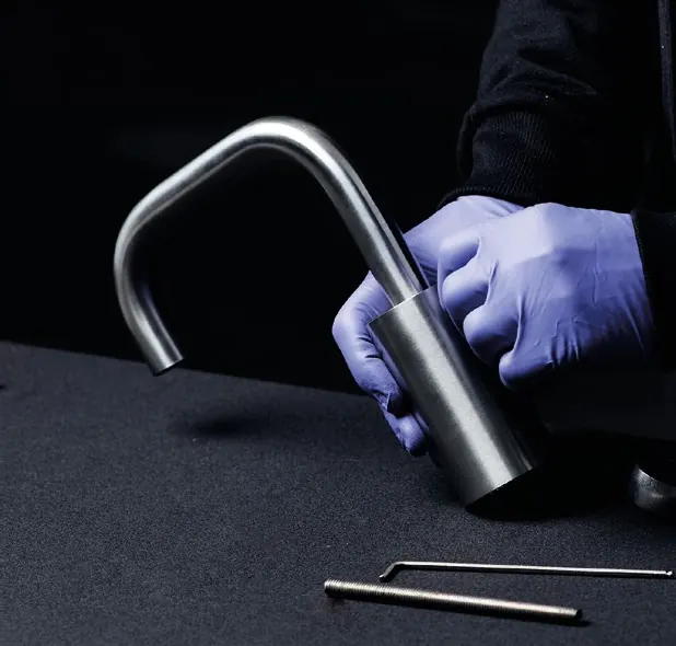 Hands assembling a brushed stainless steel tap spout in the Fontea workshop