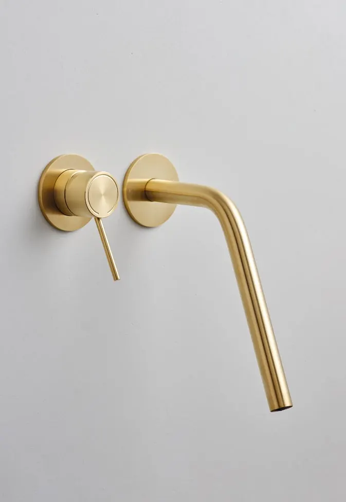 Fontea gold PVD wall-mounted tap on a pale plaster wall