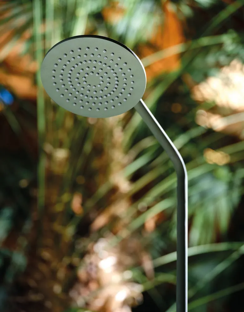A Fontea brushed stainless steel outdoor shower set against green foliage