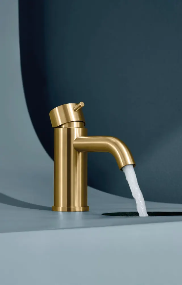 Fontea gold PVD tap running water against a deep blue backdrop