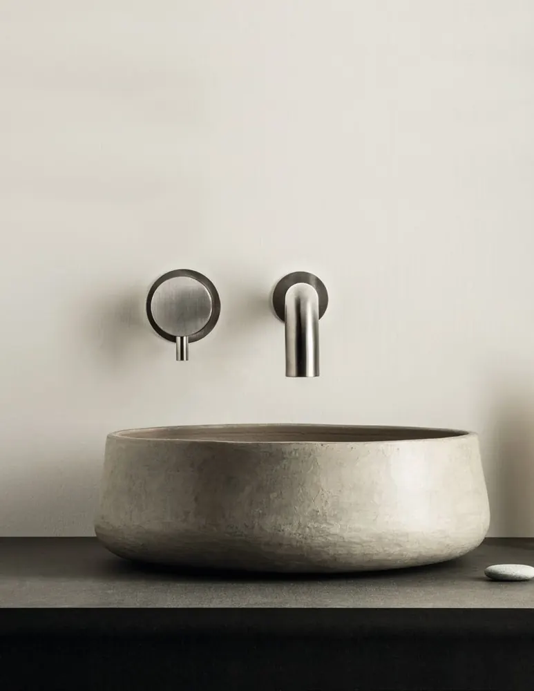 Fontea wall-mounted brushed steel tap over a stone basin